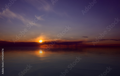 Dramatic sunset sky with clouds reflected in water surface.