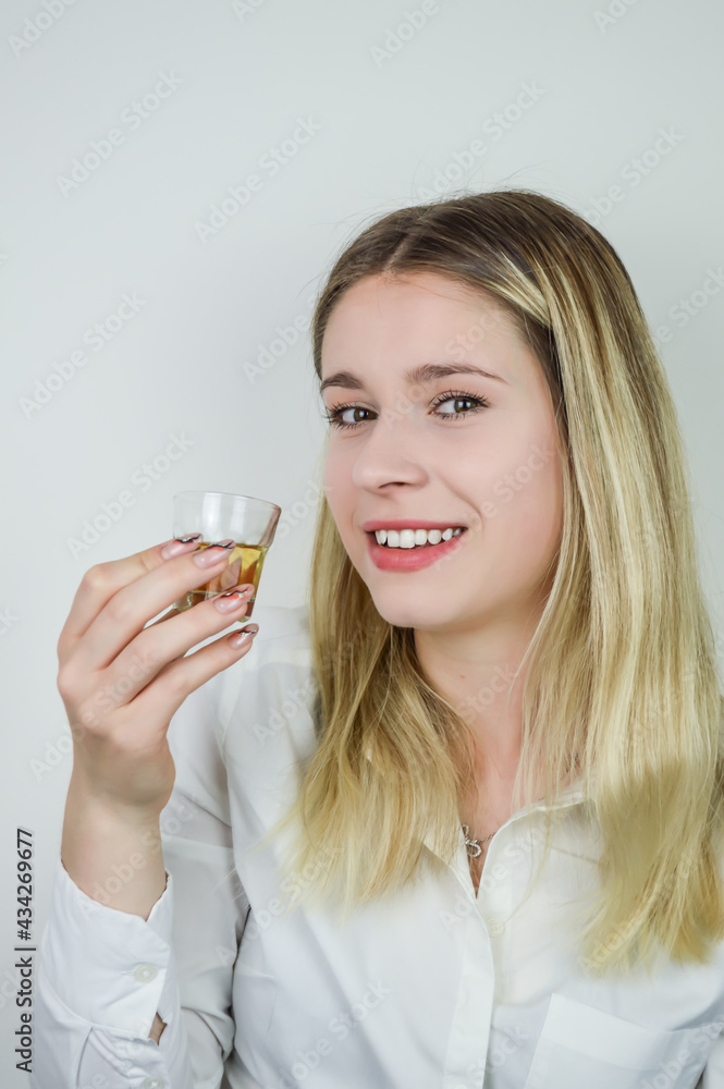 Portrait of a smiling beautiful young blonde woman holding a shot of liqueur Portrait of a smiling beautiful young blonde woman holding a shot of liqueur