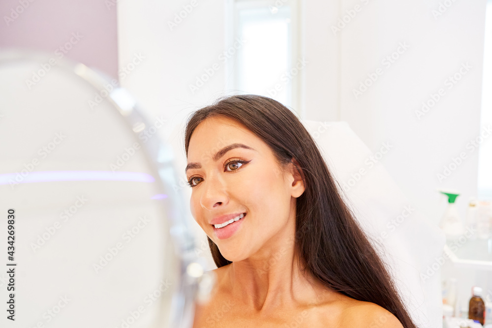 Glückliche Frau schaut auf ihr Gesicht im Spiegel Glückliche Frau schaut auf ihr Gesicht im Spiegel
