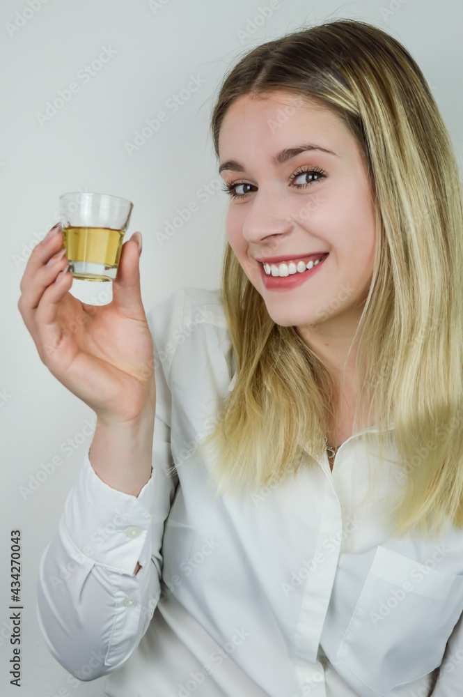 Portrait of a smiling beautiful young blonde woman holding a shot of liqueur Portrait of a smiling beautiful young blonde woman holding a shot of liqueur
