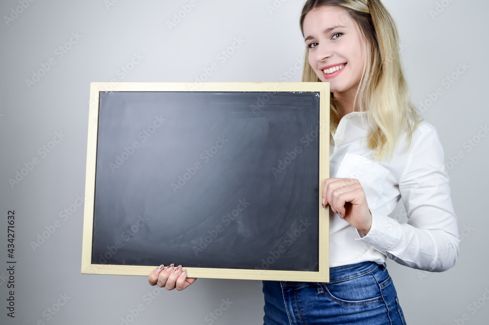 Portrait of a smiling beautiful young blonde woman holding an empty chalkboard horizontally where you can add text Portrait of a smiling beautiful young blonde woman holding an empty chalkboard horizontally where you can add text