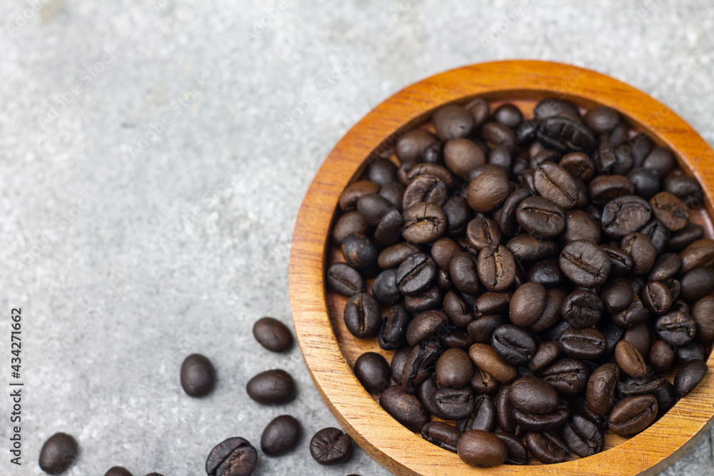 Fototapeta premium Biji Kopi or Coffee beans on wooden plate and coffee beans on grey background. Close up view. Copy space for text. 