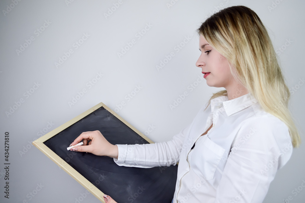Portrait of a beautiful young blonde woman writing with chalk on a blackboard Portrait of a beautiful young blonde woman writing with chalk on a blackboard