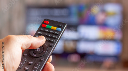 vista de una mano con un mando a distancia con una televisión delante con una aplicación de cine y series