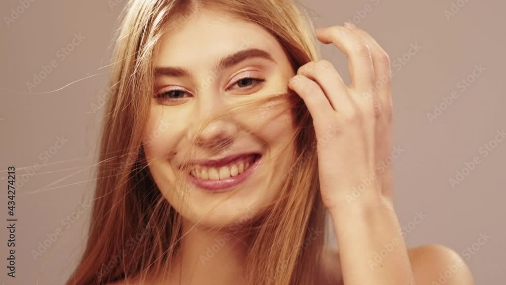 Perfect smile. Beautiful woman. Dental care. Healthy treatment. Smiling tender blonde woman with even white teeth looking at camera isolated beige slow motion. Perfect smile. Beautiful woman. Dental care. Healthy treatment. Smiling tender blonde woman with even white teeth looking at camera isolated beige slow motion.