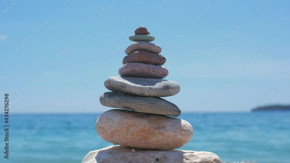 Close view to the stone pyramid on the coastline. Blue Adriatic sea on the background. Sunny weather in Montenegro Close view to the stone pyramid on the coastline. Blue Adriatic sea on the background. Sunny weather in Montenegro