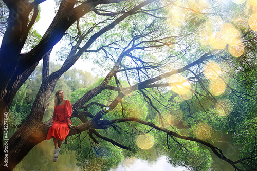 springtime dreaming female girl sitting on a tree branch, spring forest park © kichigin19