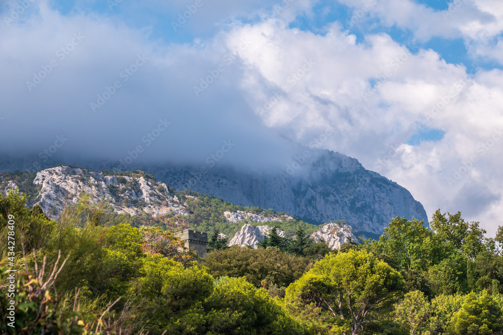 High rocky mountains with forested slopes and peaks hidden in the clouds. Ai-Petri, Crimea