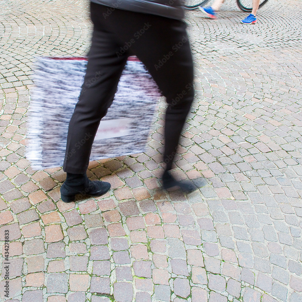 People walking in a pedestrian zone paved in little stone People walking in a pedestrian zone paved in little stone