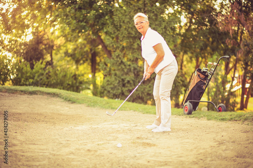 Senior woman playing golf. Good shot.