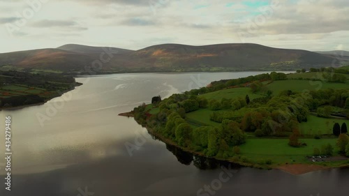 Aerial view over Irish landscape at sunrise in the Baltyboys area, County Wicklow, revealing forest, lake, and mountains. photo