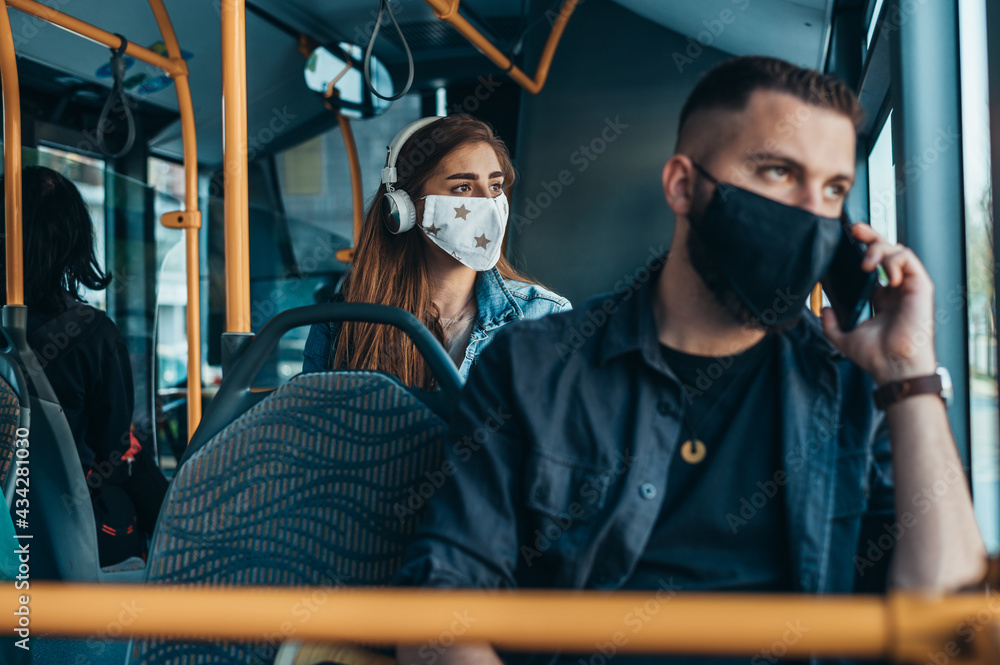 Woman wearing protective mask and using a headphones while riding a bus