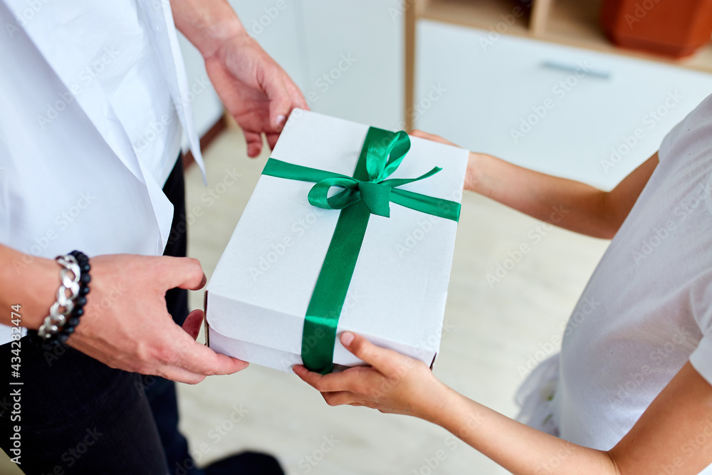 Little girl is giving her handsome father a gift box on Father's day, unrecognizable daughter congratulating dad and giving present on birthday at home. I love you, dad. Happy Father's Day.. Little girl is giving her handsome father a gift box on Father's day, unrecognizable daughter congratulating dad and giving present on birthday at home. I love you, dad. Happy Father's Day..