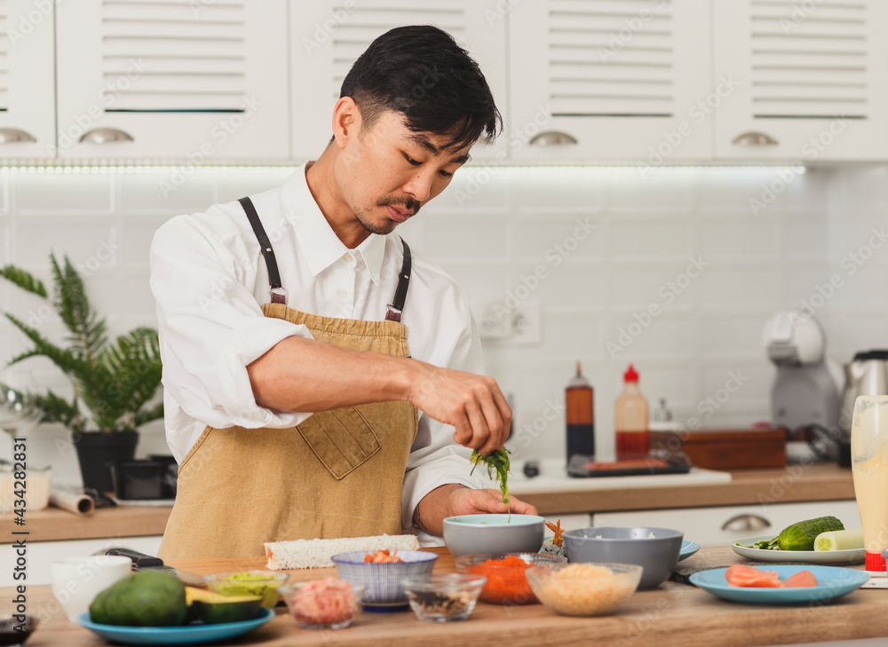 Portrait of asian chef. Sushi preparation with bamboo mat and sushi ingredients Portrait of asian chef. Sushi preparation with bamboo mat and sushi ingredients