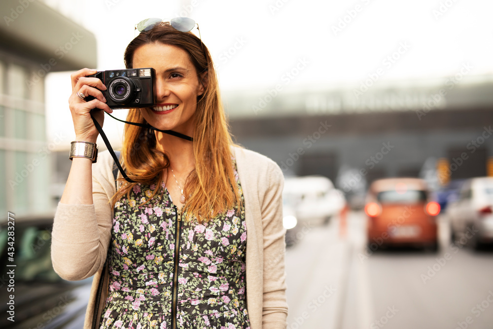 Attractive tourist with a camera. Beautiful woman with camera taking photos of beautiful location..