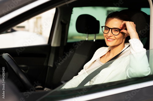 Beautiful businesswoman driving a car. Portrait of smiling woman sitting in the car. © JustLife