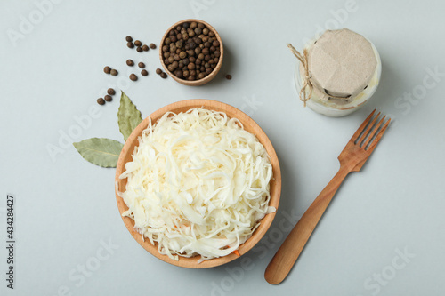 Bowl of sauerkraut and ingredients on light gray background photo