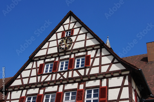 Close-up of the half-timbered town hall building of the city of Münsingen. The house has characteristic red folding shutters and an outdoor clock. photo