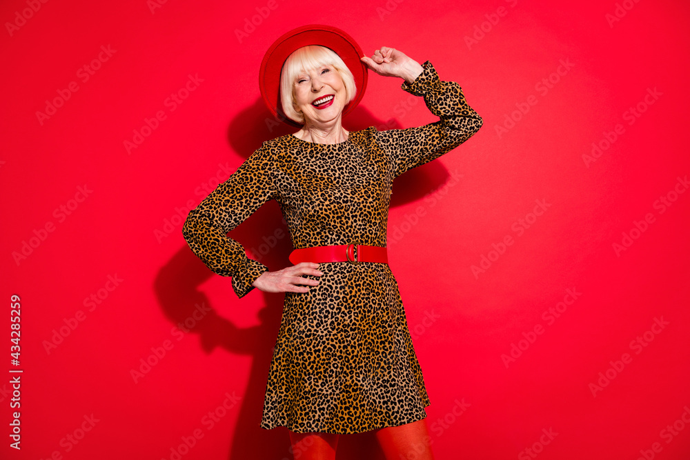 Photo of cheerful nice old happy woman hold hand hat waist good mood free time isolated on red color background Photo of cheerful nice old happy woman hold hand hat waist good mood free time isolated on red color background