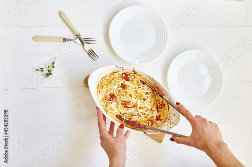 Woman hand's cooking trending viral baked tomatoes and feta with pasta photo