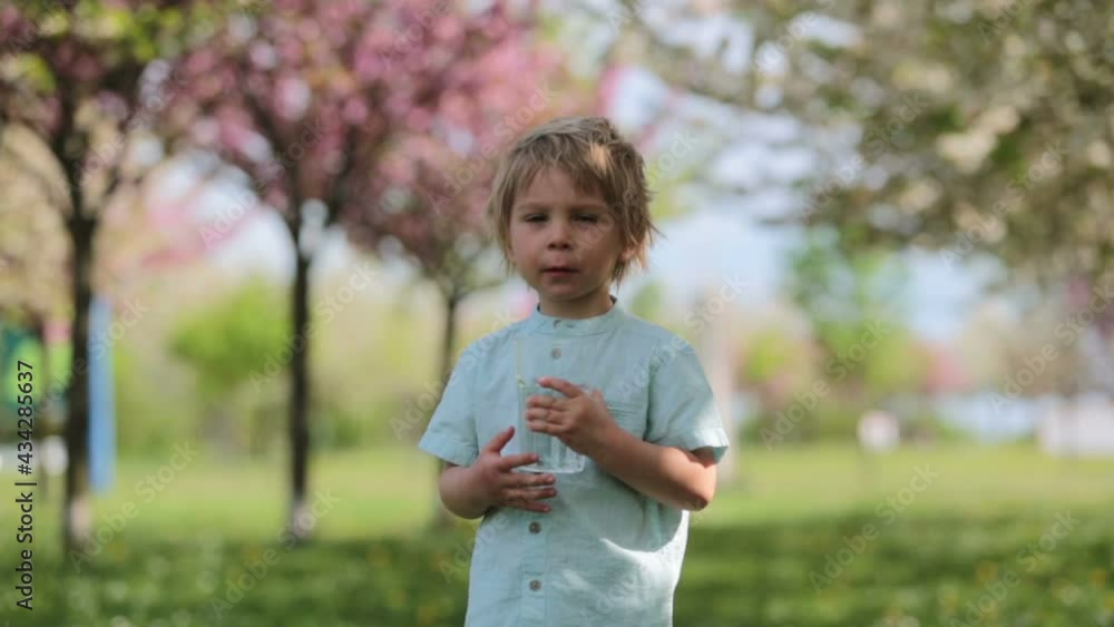 Beautiful blond child, boy, drinking water in the park on a hot summer day Beautiful blond child, boy, drinking water in the park on a hot summer day