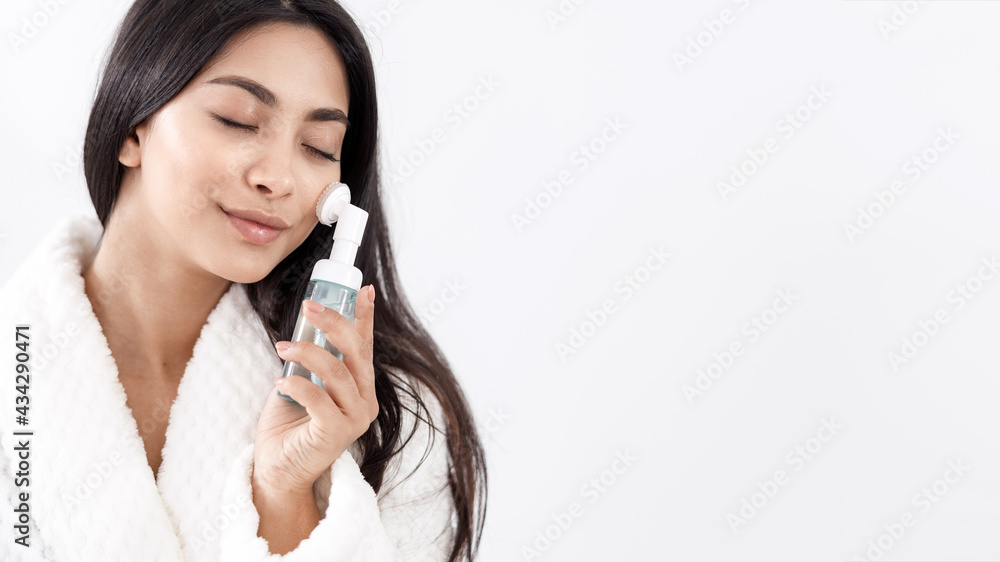 Young asian woman with face cleanser brush Young asian woman with face cleanser brush