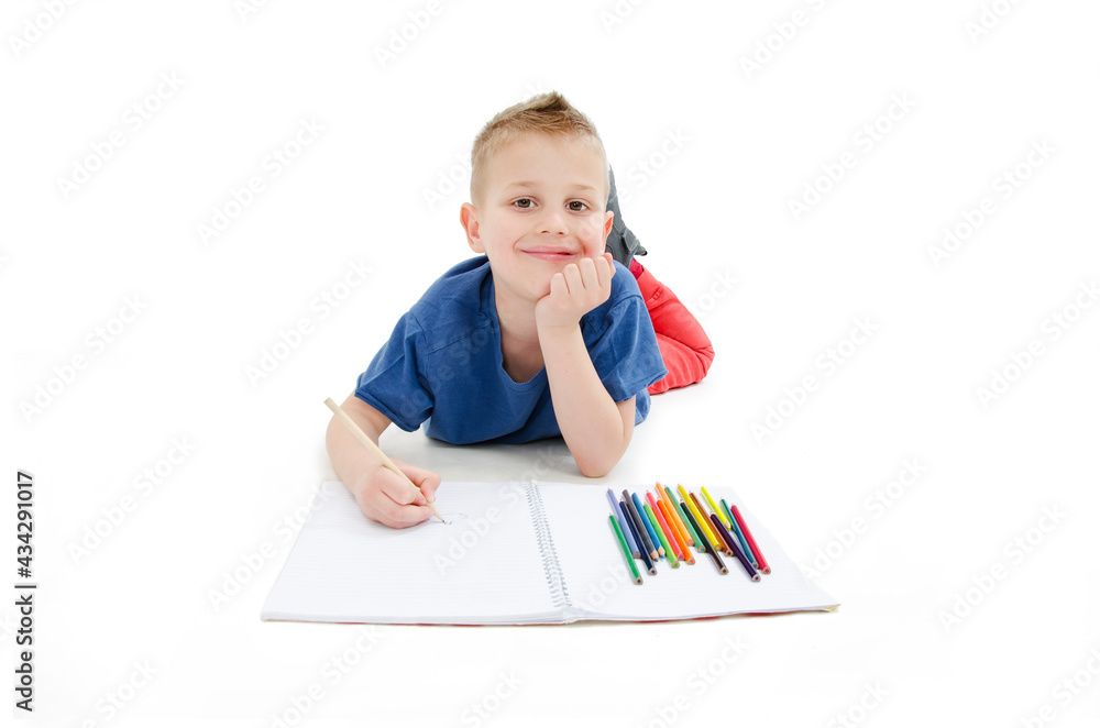 Young boy lying on floor with pencils on a sketch book with a look of concentration, close up view. Isolated on white background
Young boy lying on floor with pencils on a sketch book with a look of concentration, close up view. Isolated on white background