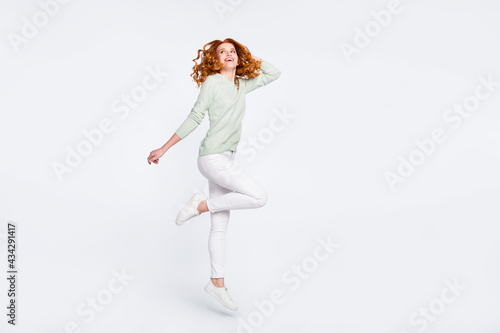 Full length body size photo young woman red hair jumping up in casual clothes dreamy looking copyspace isolated white color background © deagreez