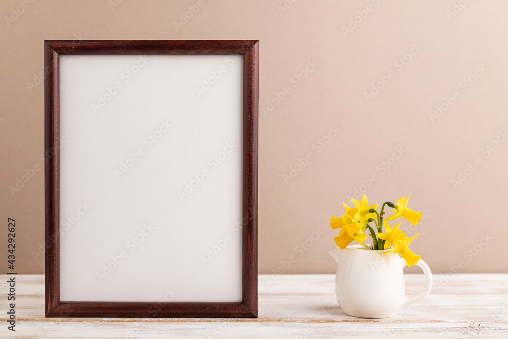 Wooden frame with spring snowdrop flowers narcissus on beige pastel background. top view, copy space, mockup, template. Wooden frame with spring snowdrop flowers narcissus on beige pastel background. top view, copy space, mockup, template.