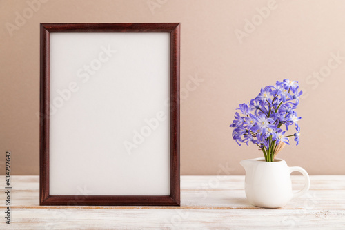 Wooden frame with spring snowdrop flowers chionodox on beige pastel background. top view, copy space, mockup, template.
