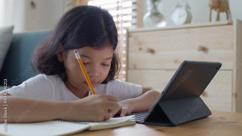 Asian little girl do homework and learning online via  internet tutor on tablet 