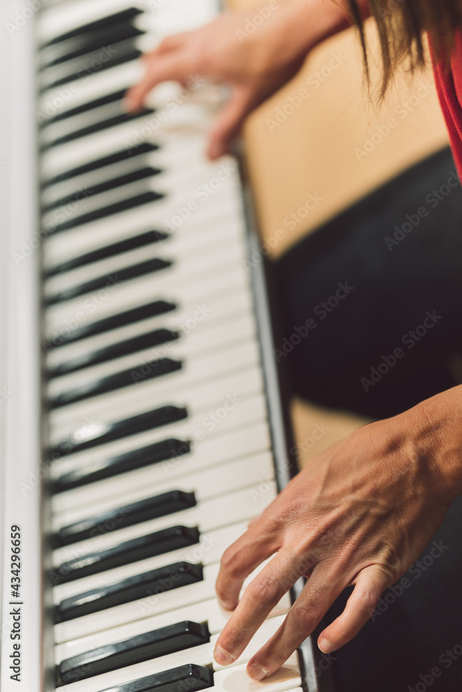 Obraz premium Vertical photo of a woman playing electronic piano