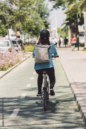 Woman riding a bicycle in the street with a backpack © Samuel Perales