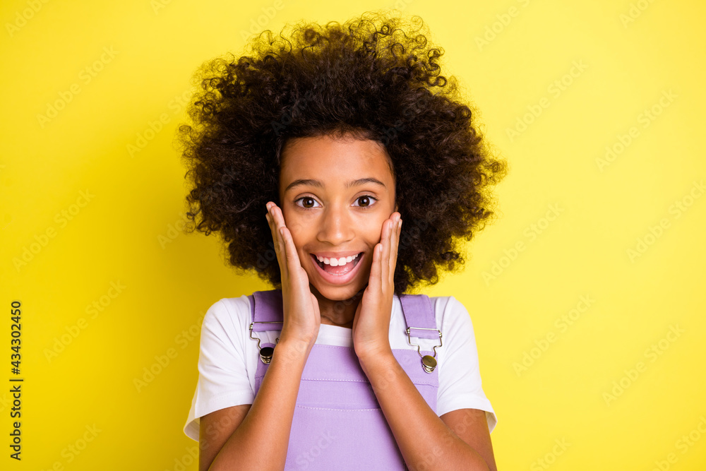 Portrait of pretty amazed cheerful wavy-haired girl enjoying great news isolated over bright yellow color background Portrait of pretty amazed cheerful wavy-haired girl enjoying great news isolated over bright yellow color background