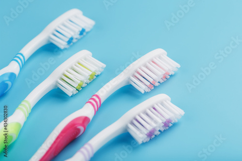 Toothbrushes of different colors in a row on a blue background.