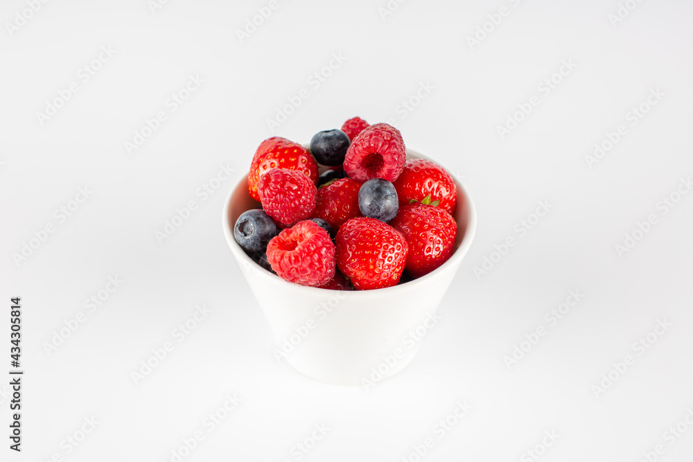 strawberries, raspberries, blueberries in a white bowl on a white background strawberries, raspberries, blueberries in a white bowl on a white background