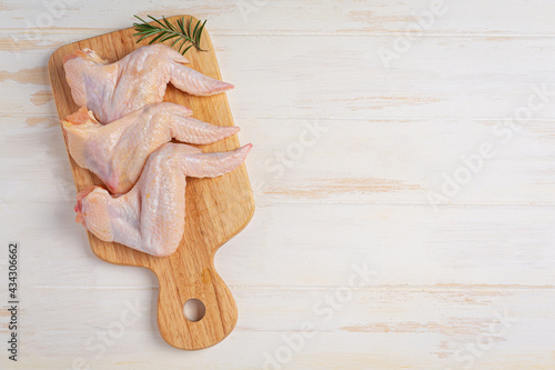 Raw chicken wings on the white wooden background.