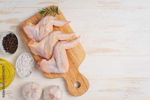 Raw chicken wings on the white wooden background.