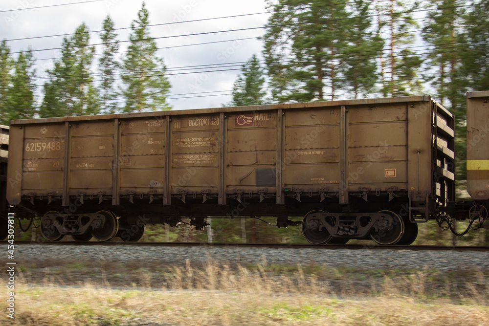 A gondola car as part of a train. A gondola car as part of a freight train rushes along the rails.