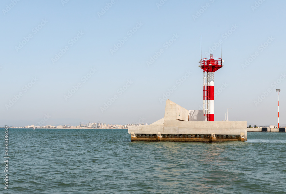 A small lighthouse is located on the breakwater at the exit from the water area in the Mediterranean port of Haifa in Israel