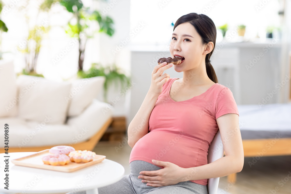 Asian pregnant woman eat donuts Asian pregnant woman eat donuts