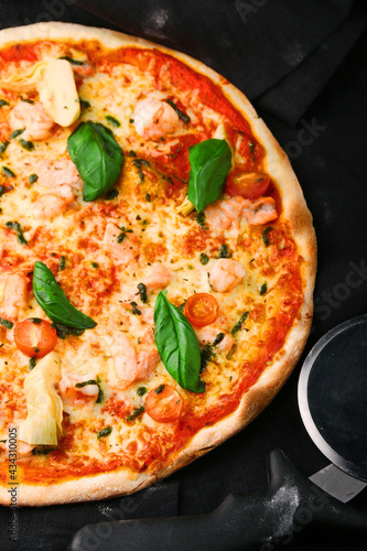 seafood pizza with shrimp and tomatoes on dark background top and pizza knife
