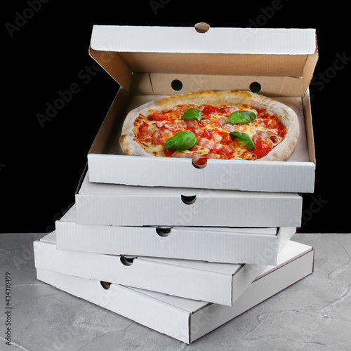 stack of pizza box with pizza inside. pizza delivery. box on black background. meat pizza