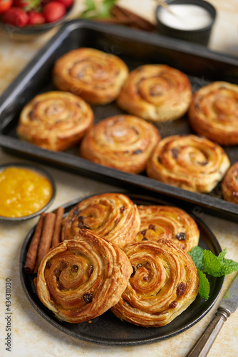 Delicious, fresh baked cinnamon buns served on black ceramic plate. With various sides
