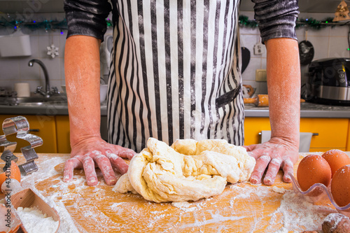 Fotografie An inept inexperienced housewife, a woman cook, does not know how to knead the dough correctly, asks for advice