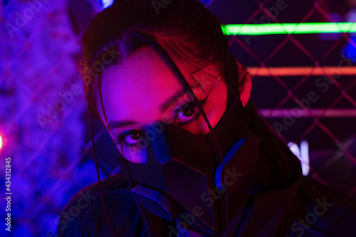 neon lighting on young asian woman in gas mask looking at camera