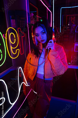 Fotografie neon lighting on stylish young asian woman talking on retro payphone outside