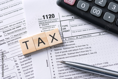 Tax word made of wooden tiles. US tax form on desk