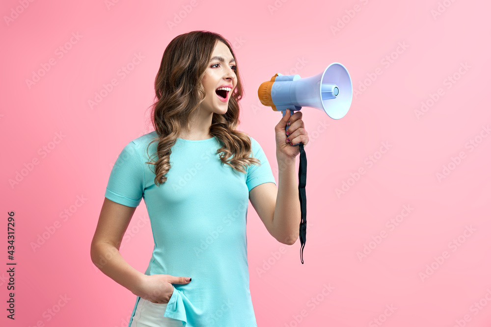 Cheerful young woman shouting in megaphone on pink background Cheerful young woman shouting in megaphone on pink background