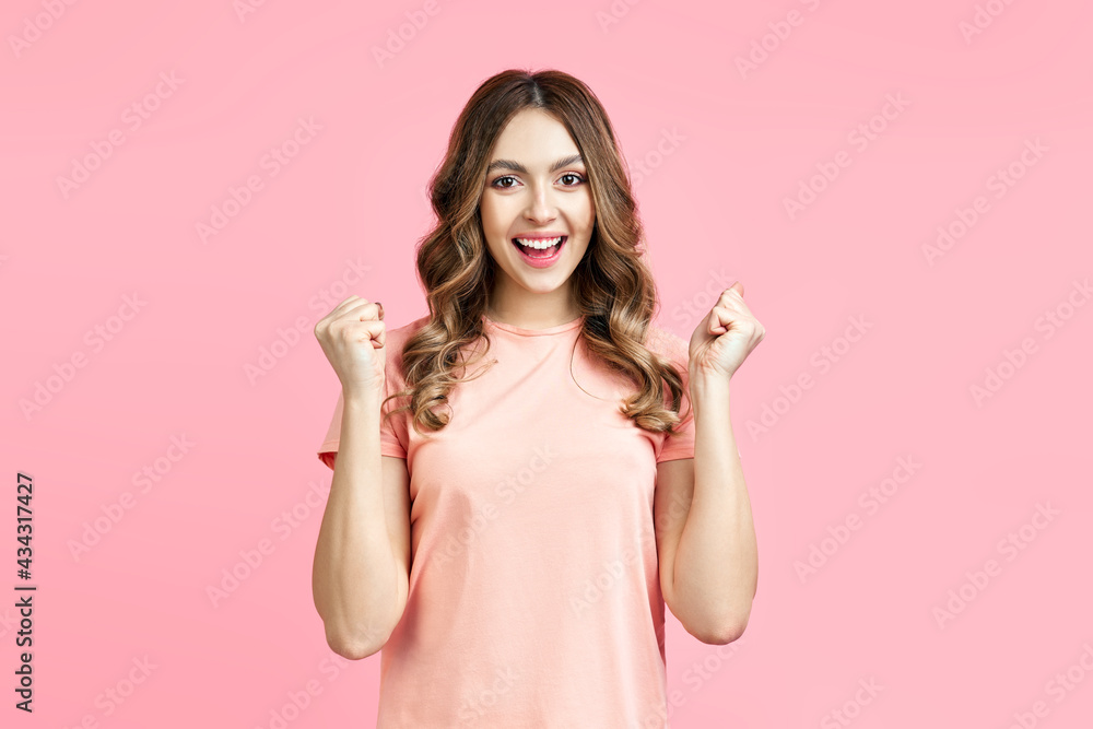 Happy excited young woman celebrate success with hands up isolated on pink background Happy excited young woman celebrate success with hands up isolated on pink background